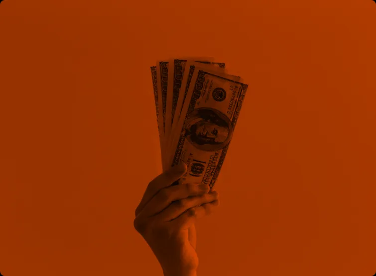 A hand holds a fan of banknotes.